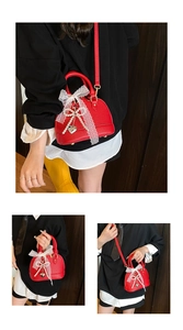 Detail of red shell bag with lychee pattern, white lace bow, and pearl charm accents