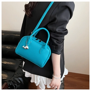 Detail view of turquoise lychee pattern handbag with silver whale pendant charm