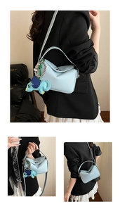 Détail du sac croissant bleu clair avec texture de cuir et pendentif éléphant
