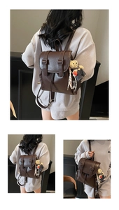 Détail d'un sac à dos en cuir PU marron foncé avec boucle vintage et breloque ours