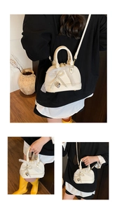 Detail of cream shell bag with lace bow, pearl charms and silver heart pendant detail