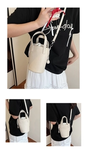 Détail du sac seau crème montrant le cuir grainé et la pochette intérieure avec cordon de serrage