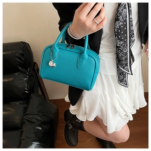 Detail of teal Boston bag with lychee texture and silver elephant charm accessory