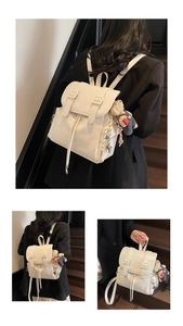 Détail d'un sac à dos en cuir blanc crème avec deux sangles et un pendentif d'ours