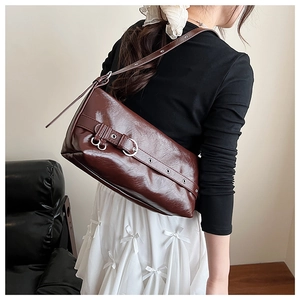 Detailed view of dark brown glossy leather underarm bag with belt buckle decoration