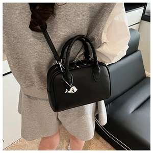 Detail view of black pebble leather Boston bag with whale charm on a female model