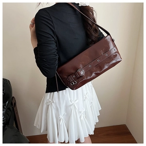 Detail of dark brown glossy patent leather shoulder bag with decorative belt buckle element