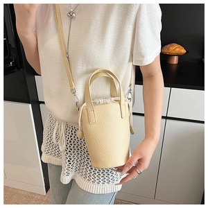 Close-up of mini light yellow bucket bag with drawstring inner and lychee leather texture