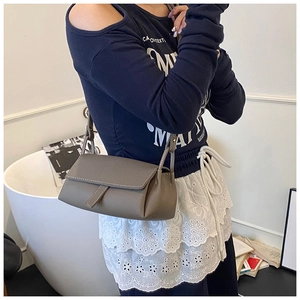 Detail of taupe lychee texture pillow bag with white contrast stitching and adjustable strap