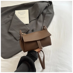 Detail of brown litchi pattern leather bag showing texture and snap closure