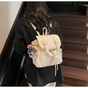 Détail du sac à dos crème avec fermeture à cordon et joli petit ours en peluche