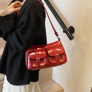 Chic red patent leather moto-style tote bag with dual front buckle pockets on a shoulder strap