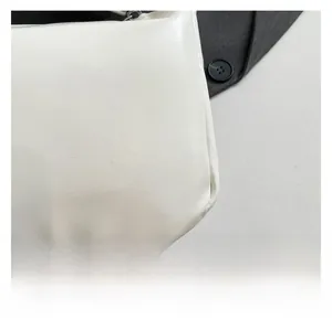 Gros plan détaillé sur la texture du cuir blanc avec des coutures soignées sur un petit sac