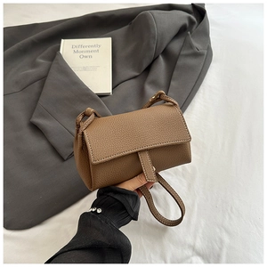 Detail of brown lychee grain leather mini bag with flap closure and vertical strap