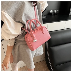 Detailed texture of pink litchi grain leather bowling bag with silver whale charm