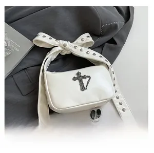 Vue macro du sac gothique blanc avec bandoulière à nœud riveté et détail de croix