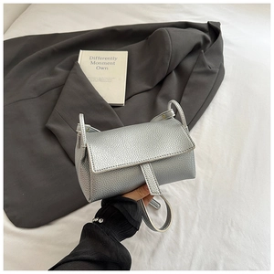 Detailed view of silver lychee texture leather on a small square flap crossbody bag