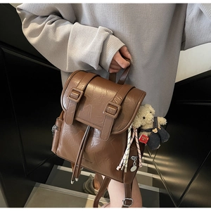 Dettaglio di uno zaino vintage marrone con fibbia e ciondolo a forma di orsetto