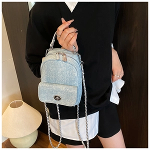 Detail of light blue denim mini backpack with silver chain strap and metal swivel lock