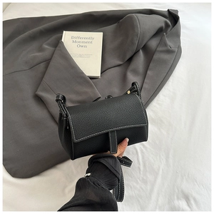 Close-up of black lychee grain leather pillow bag with elegant white contrast stitching