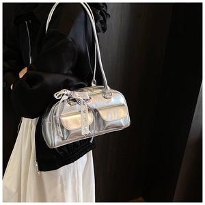 Detailed close-up of a silver metallic shoulder bag featuring dual pockets and ribbon charm