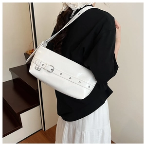 Detail view of white glossy leather shoulder bag with silver buckles and metal rivets
