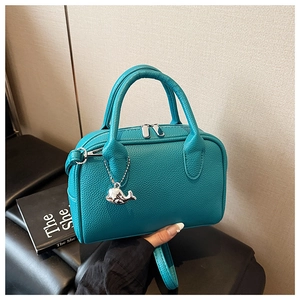 Close-up of pebble leather texture and whale charm on a mint green Boston bag