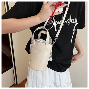 Close-up of cream bucket bag with lychee grain texture and drawstring inner pouch