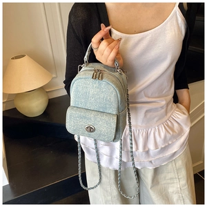 Detail of light blue denim mini backpack with silver metal hardware and chain strap