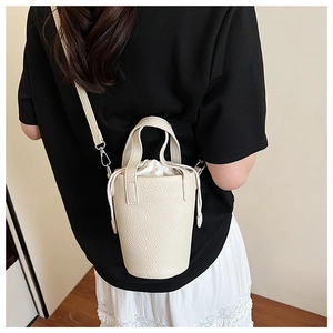 Detailed back view of model wearing a beige pebbled leather bucket bag with crossbody strap