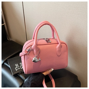 Detail of pink pebbled leather Boston bag with silver whale charm and dual zippers