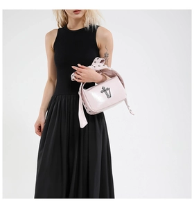 Close-up of pink gothic cross handbag with silver metal studs on a black dress model