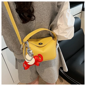 Détail du sac à main en cuir grainé jaune avec breloque éléphant et chaîne cœur
