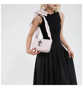 Détail du sac gothique rose clair avec croix en métal et bandoulière à œillets