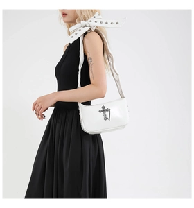 Détail du sac gothique blanc avec croix métallique et bandoulière à nœud riveté