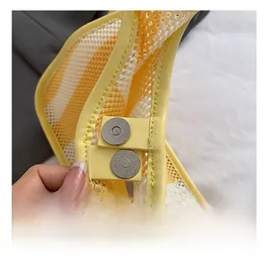 Detail of silver magnetic buckle on yellow and white striped mesh crossbody bag