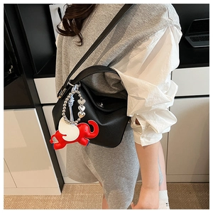 Détail d'un sac bandoulière en cuir grainé noir avec charme éléphant rouge et boucles argentées