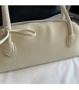 Detail of cream white boston bag showing litchi grain texture and silver zipper