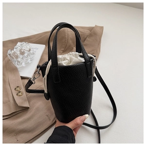 Détail d'un sac seau noir en cuir grainé avec pochette intérieure blanche et boucles argentées