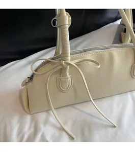 Close-up of cream shell bag with decorative bow and wrapped handle texture detail