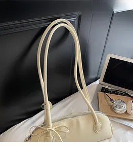 Detail of cream leather baguette bag with knotted bow accent and smooth shoulder strap