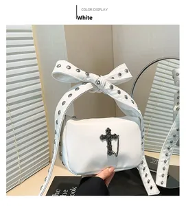 Close-up of a white tote bag with a studded bow handle and Gothic cross detail