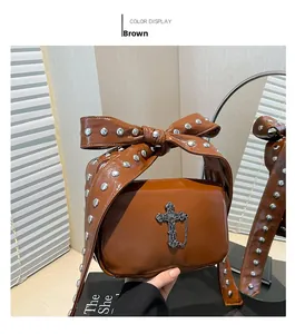 Close-up of brown handbag with silver rivets on bow handle and cross charm detail