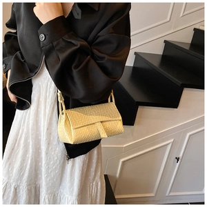 Détail de la texture tressée du sac à rabat crème avec sa fine bandoulière élégante