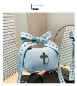 Detail of light blue punk bag featuring studded bow strap and black metal cross