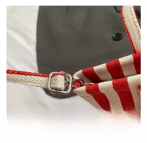 Detail der verstellbaren Metallschnalle am rot-weiß gestreiften Canvas-Taschenriemen