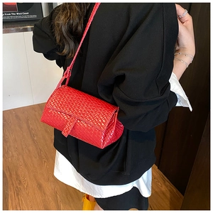 Detailed close-up of the bright red woven texture and flap design on a crossbody bag