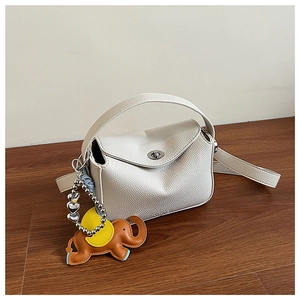 Détail du cuir litchi blanc et du pendentif éléphant brun sur le sac en demi-lune