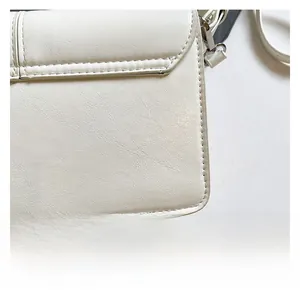 Macro shot of off-white leather shoulder bag with detailed stitching and soft texture