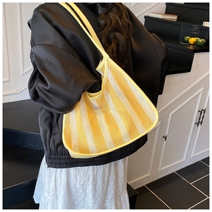 Detailed shot of yellow and white striped mesh shoulder bag on a model in a stairwell